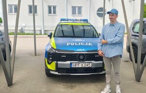 chłopiec stoi przed radiowozem policyjnym.