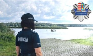 policjantka stoi przy zbiorniku wodnym, na wodzie pływa łódka.