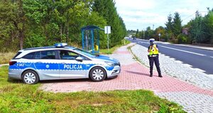 policjantka stoi na drodze obok radiowóz.