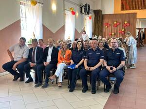 grupa ludzi, policjanci siedzą w sali na krzesłach.