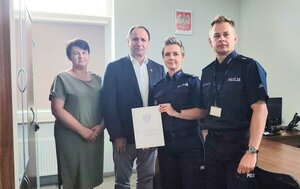 policjant i policjantka oraz kobieta i mężczyzna stoją obok siebie, trzymają dokument.