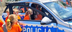 dzieci w kolorowych koszulkach znajdują się w radiowozie policyjnym.