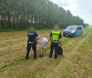policjanci trzymają mężczyznę, przed nimi radiowóz.