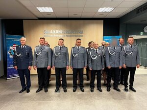 policjanci w wyjściowych mundurach stoją na sali konferencyjnej.