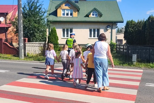dzieci z policjantem znajdują się na przejściu dla pieszych.