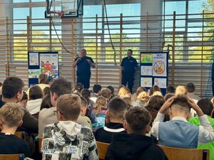 Policjanci rozmawiają z dziećmi na sali gimnastycznej.