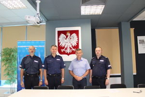 komendnat  powiatowy, zastepca komendnata kieronik posterunku oraz burmistrz pozuja do zdjecia po podpisanym porozumienu stoja  w tle godlo panstwoe